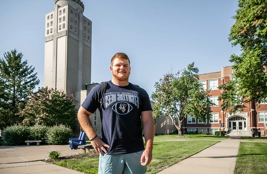 Kaeden Hutchens stands in front of academic buildings on St. Ambrose University.